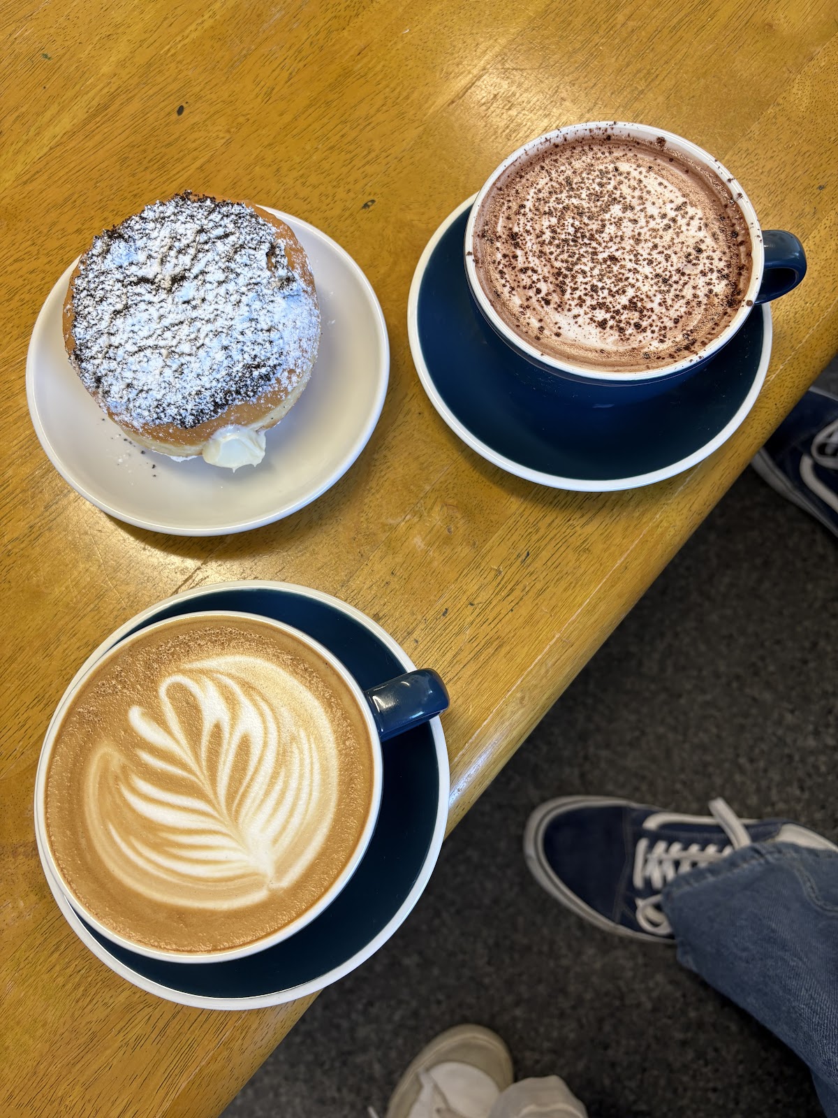 Flat white with latte art, hot chocolate and a cream donut at Coffee with J